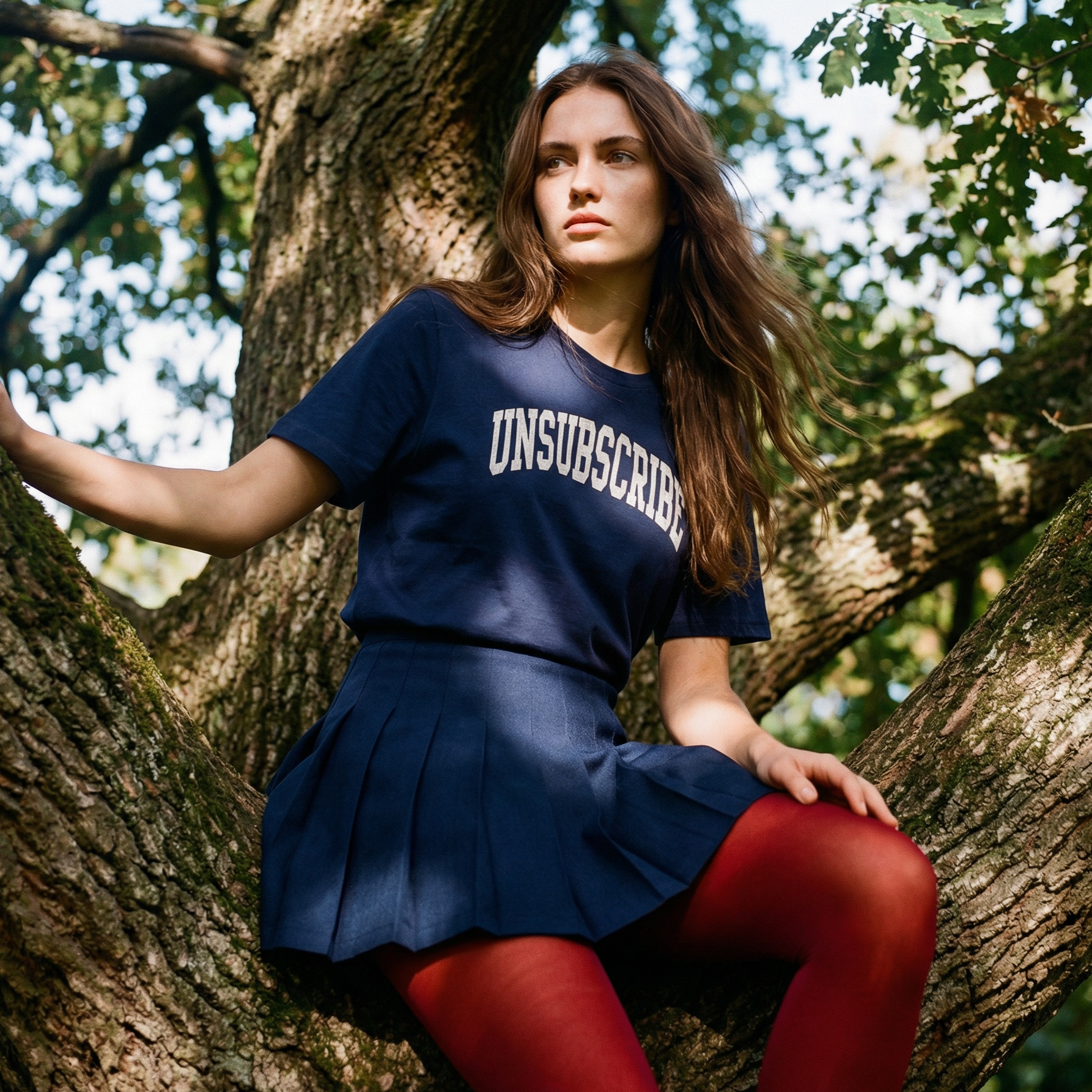 Woman in a blue 'UNSUBSCRIBE' shirt sitting in a tree